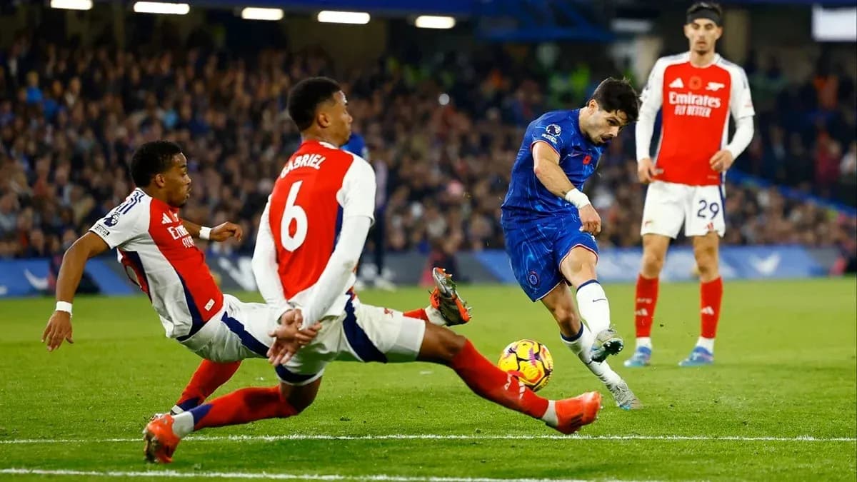 Jugador de Chelsea disparando mientras dos defensores de Arsenal intentan bloquear Jugador de Chelsea disparando mientras dos defensores de Arsenal intentan bloquear