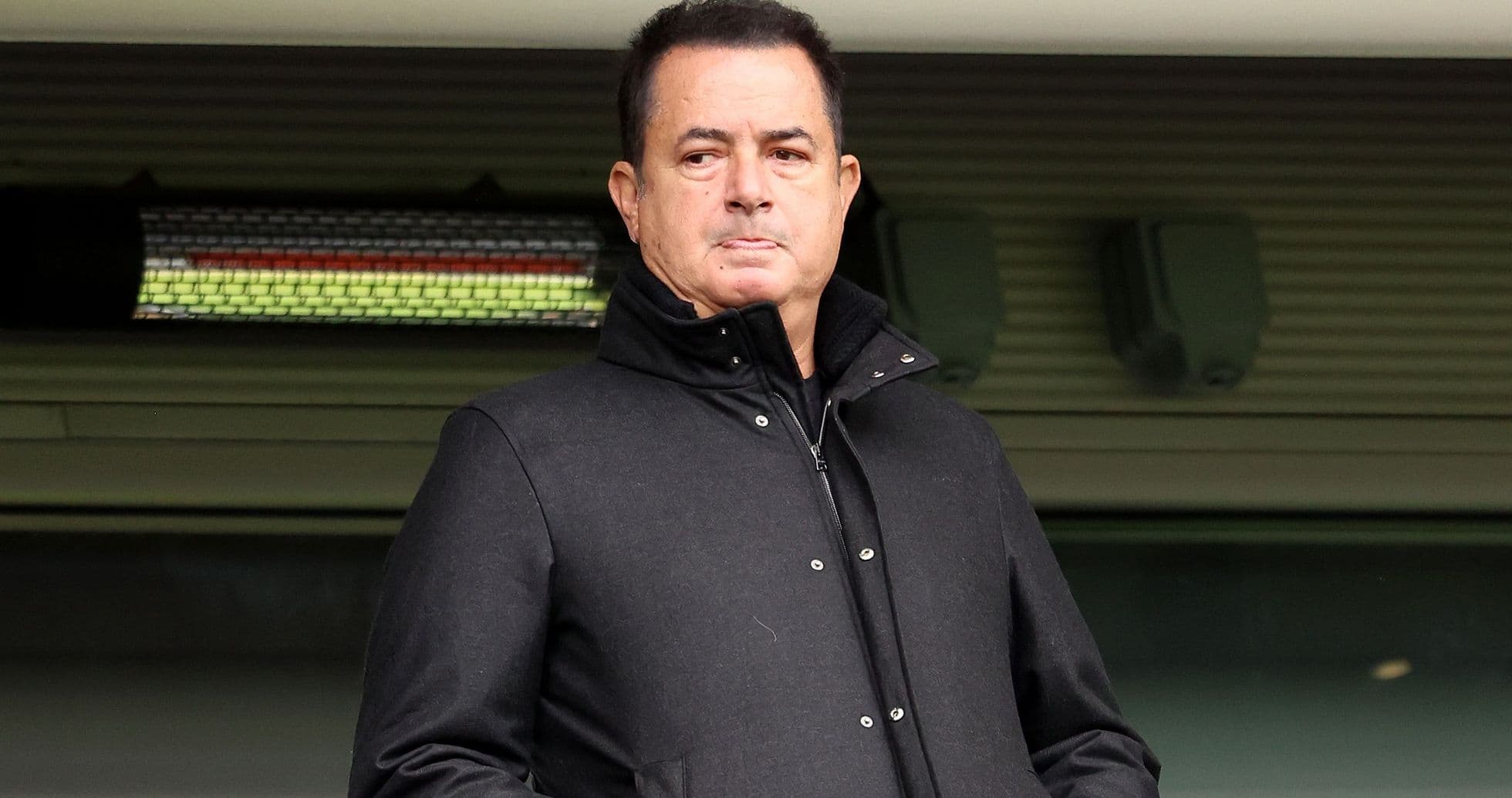 Hombre en abrigo negro observando desde una tribuna Hombre en abrigo negro observando desde una tribuna