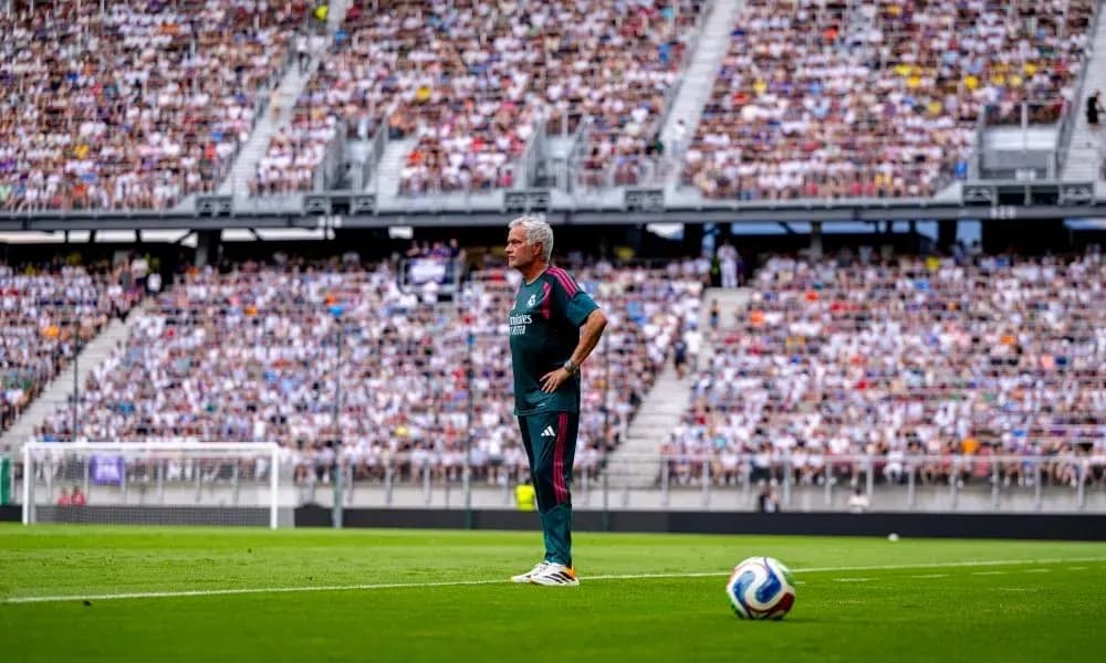 Entrenador de pie en campo con público detrás Entrenador de pie en campo con público detrás