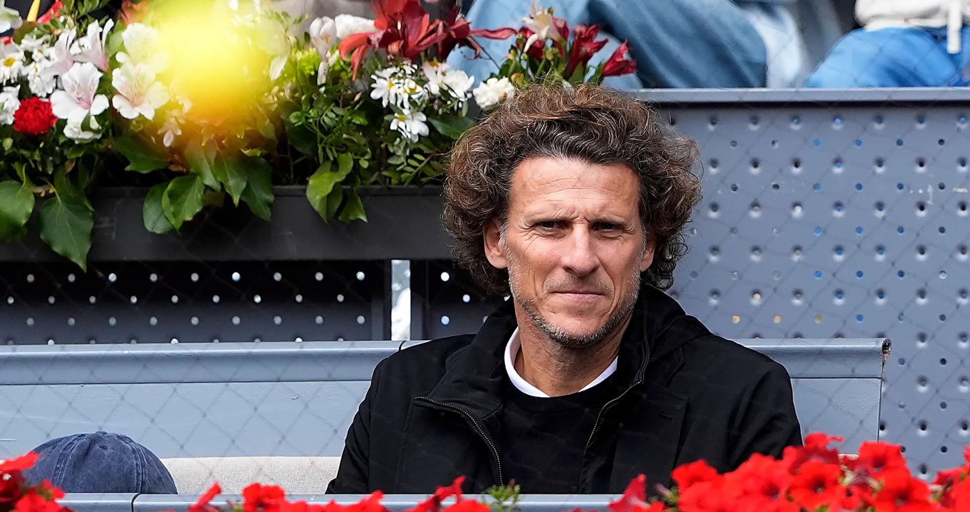 Hombre sentado frente a flores en un evento deportivo Hombre sentado frente a flores en un evento deportivo